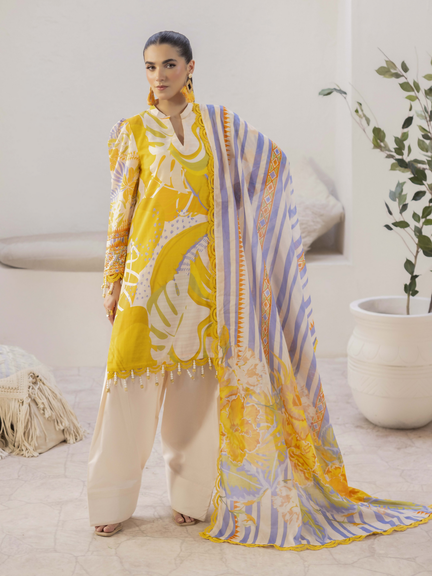 Girl standing wearing an unstitched 3-piece suit with premium digital printed slub lawn shirt, digitally printed pure voile dupatta, and dyed cotton trouser, perfect for vibrant and breathable summer wear