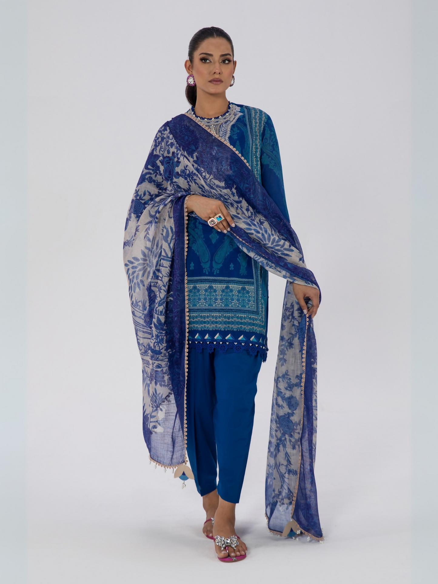 Woman wearing a blue unstitched 3-piece Sana Safinaz lawn suit with printed shirt, printed dupatta, and dyed trouser.