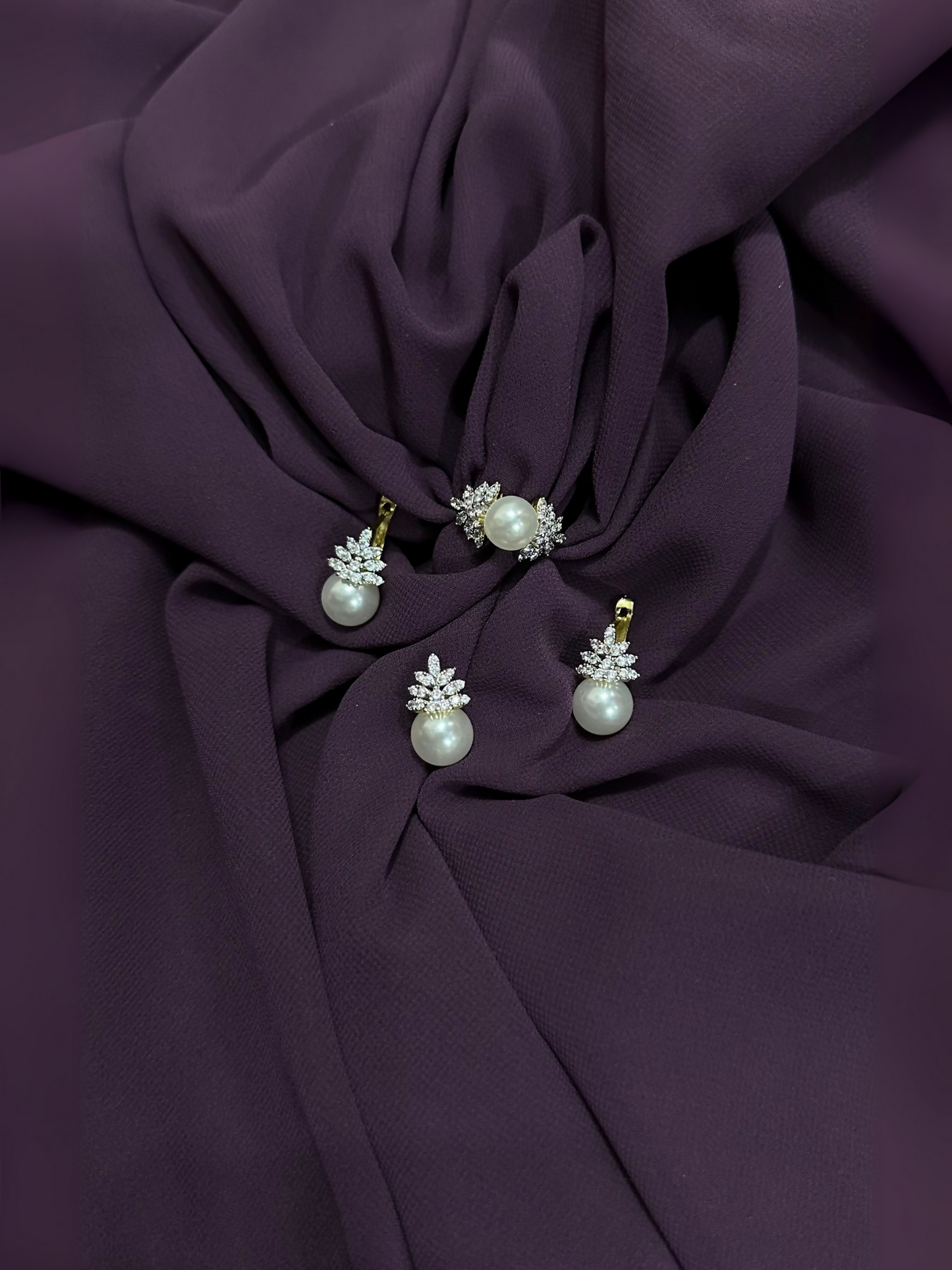 Pearl jewelry set including earrings, a pendant necklace, and a ring, each adorned with white pearls and clear crystal accents in a floral design.