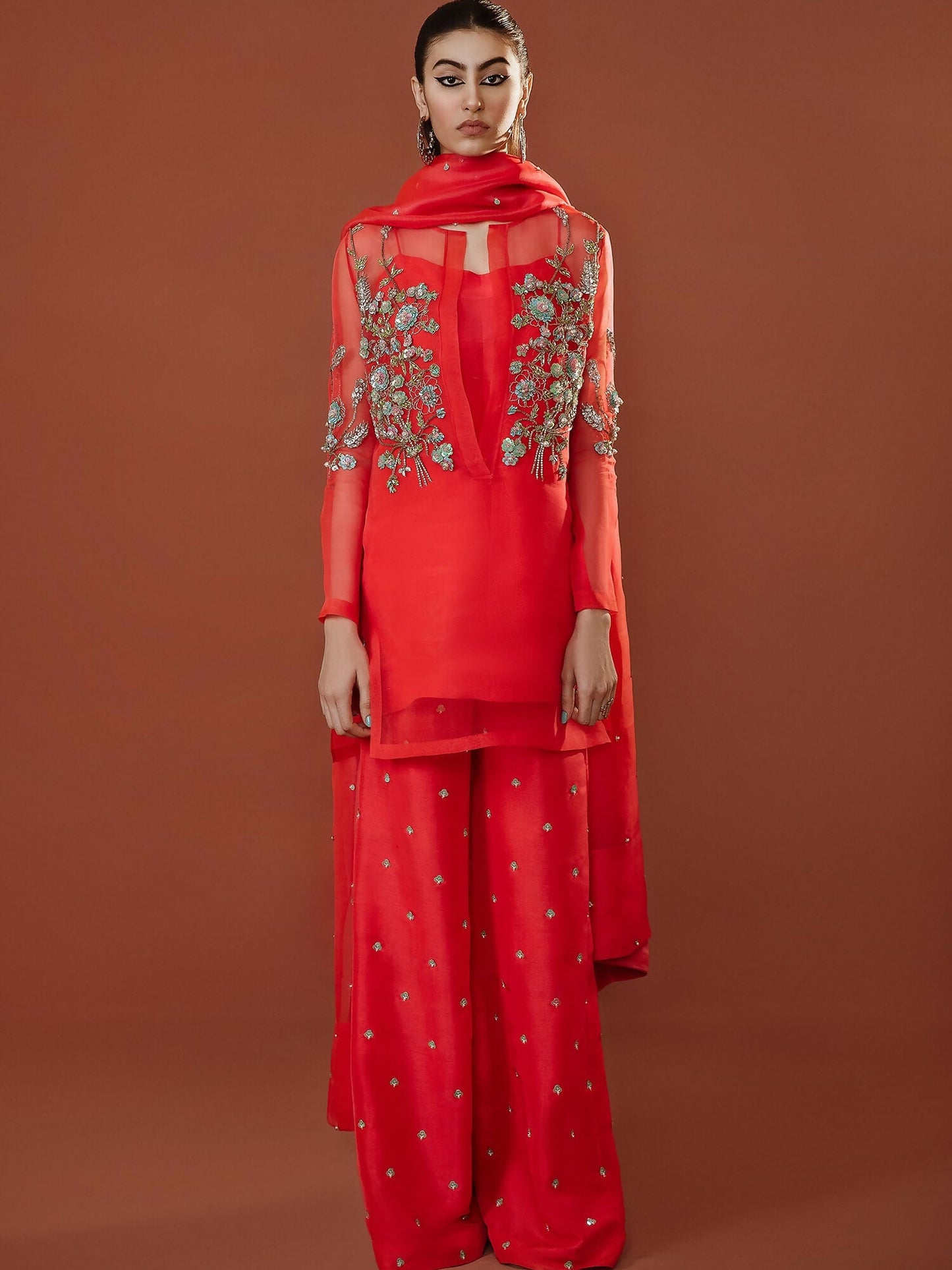 Stark carrot pink organza outfit with turquoise floral sequin and pearl embellishments, palazzo pants, and hand-embellished dupatta by Hussain Rehar.