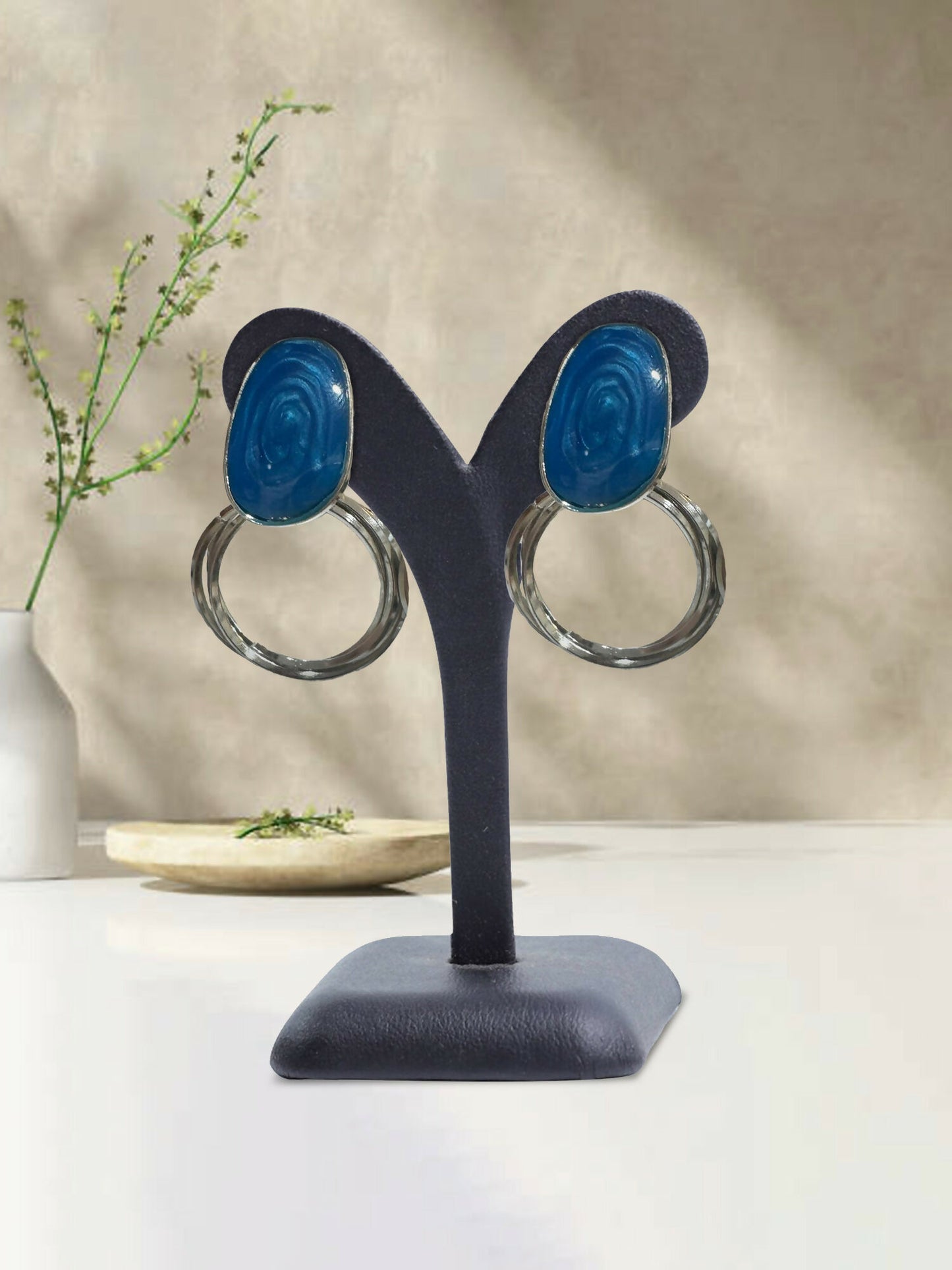 Glitter Jewellery blue dangle earrings with glossy resin tops and clear circular drops displayed on an earring stand.