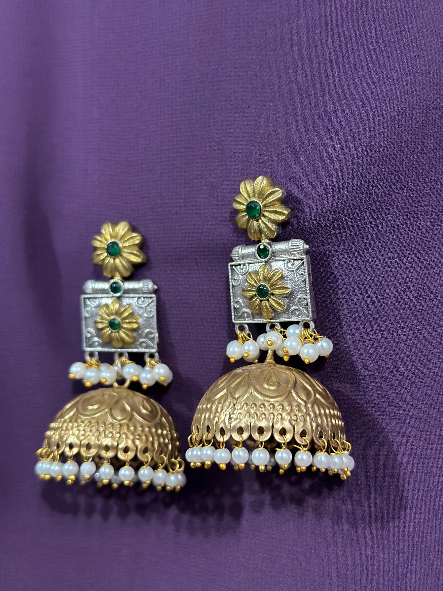 Glitter Jewellery dual-tone floral jhumka earrings with pearl clusters and green stone detailing.