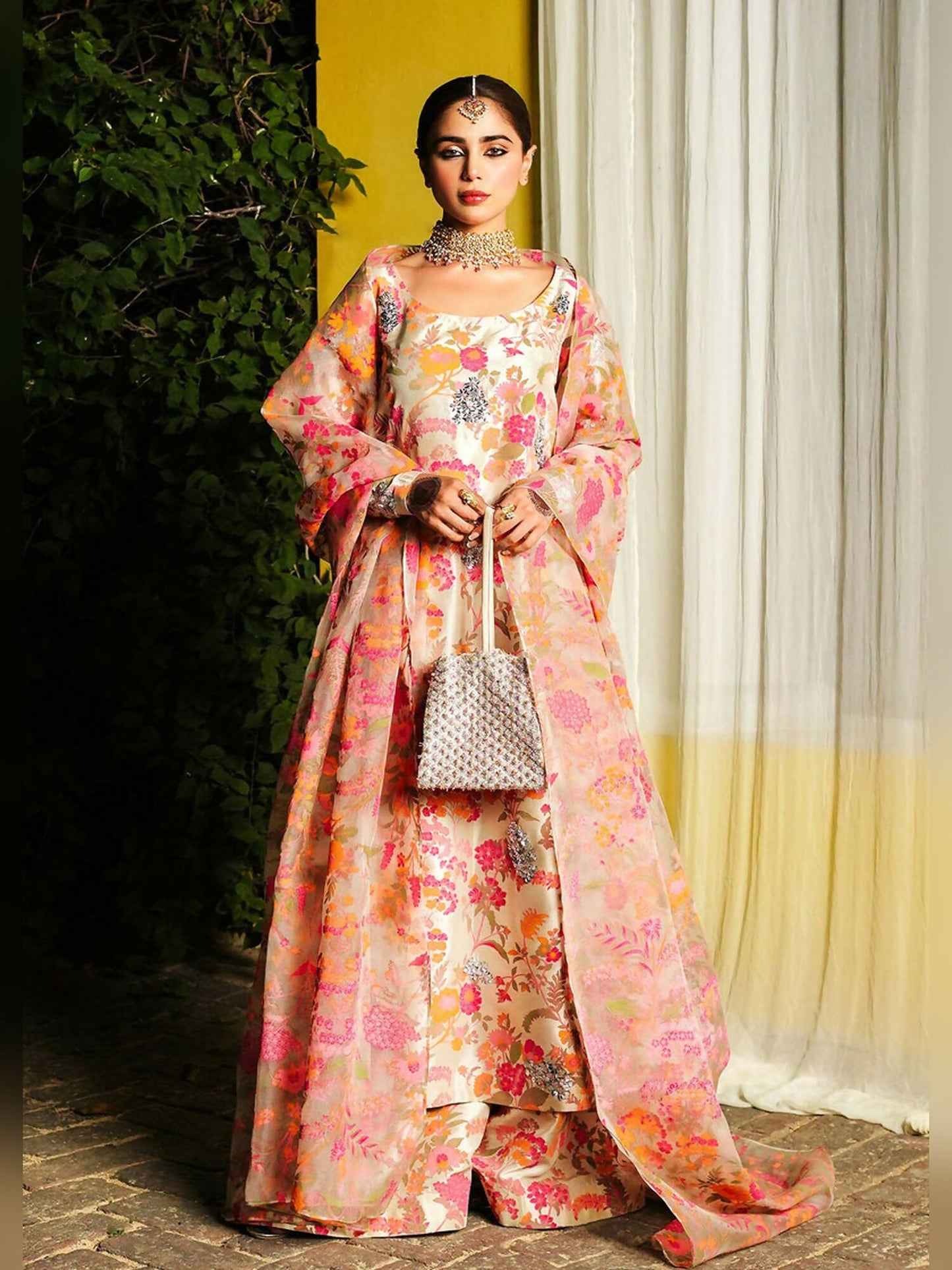 Stitched 3-piece suit by Hussain Rehar with beige long raw silk shirt featuring embellished neckline and sleeves with pita work, paired with raw silk palazzo pants and organza dupatta with kiran and golden pipe hangings.