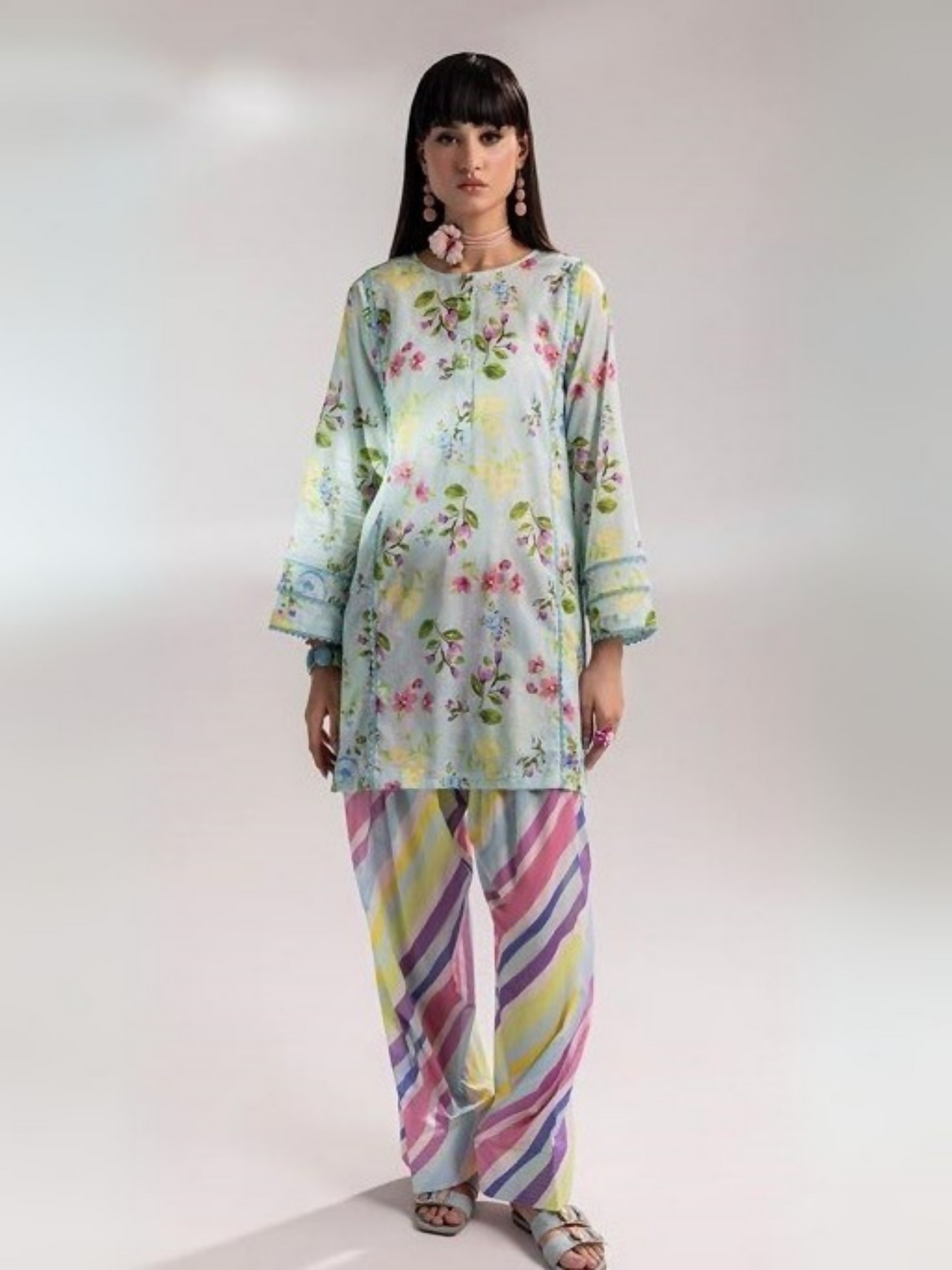 Woman wearing a pastel blue floral printed shirt with multicolor striped trousers from Parizad's unstitched lawn collection.