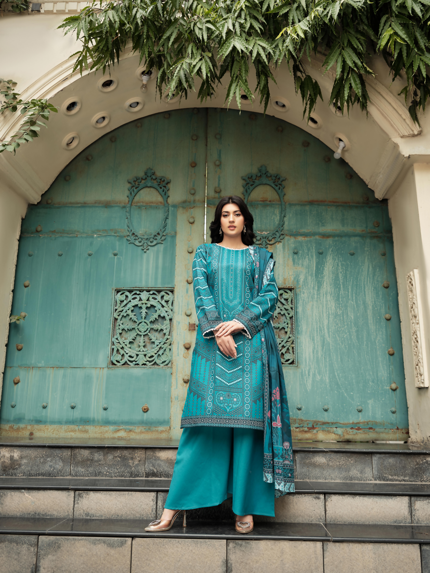 Unstitched 3-piece suit from Motifz showcasing a teal digital printed lawn shirt with geometric and floral details, paired with a matching floral printed dupatta and plain dyed trousers.