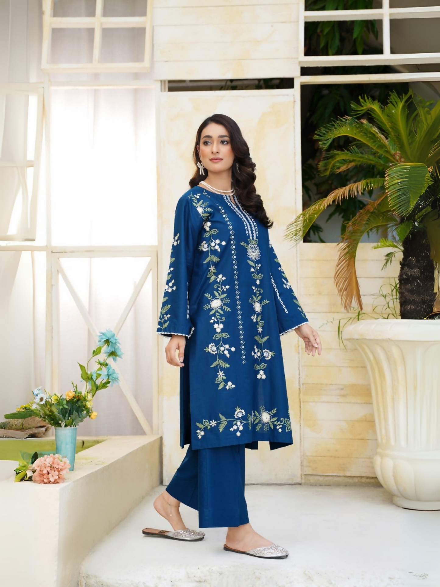 Girl wearing Trends Forever deep blue lawn cotton embroidered kurta with ivory and green floral motifs and matching straight trouser; stitched 2-piece suit.