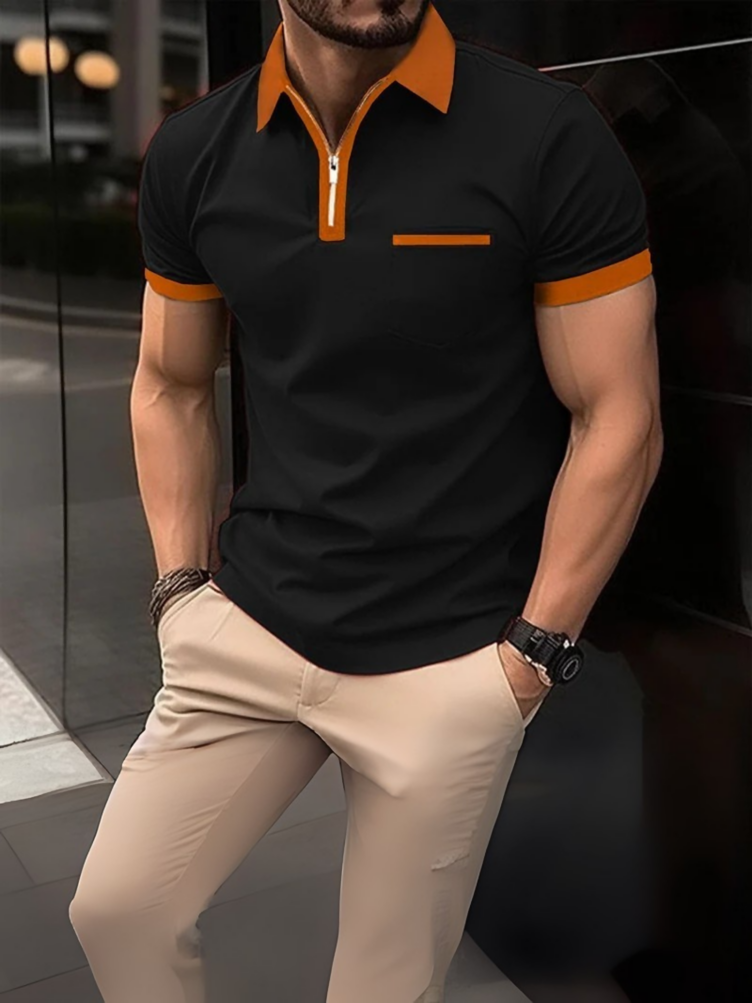 Man wearing a short-sleeve polo shirt with a zipper collar, paired with light-colored trousers, standing with hands in pockets