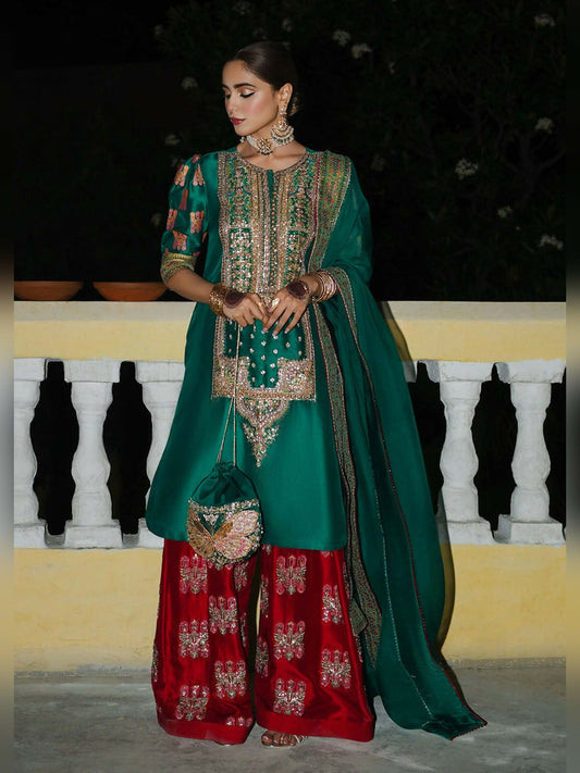Stitched 3-piece suit by Hussain Rehar with green raw silk shirt featuring embellished neckline and block-printed puff sleeves, paired with red embellished shalwar and green organza dupatta with printed border
