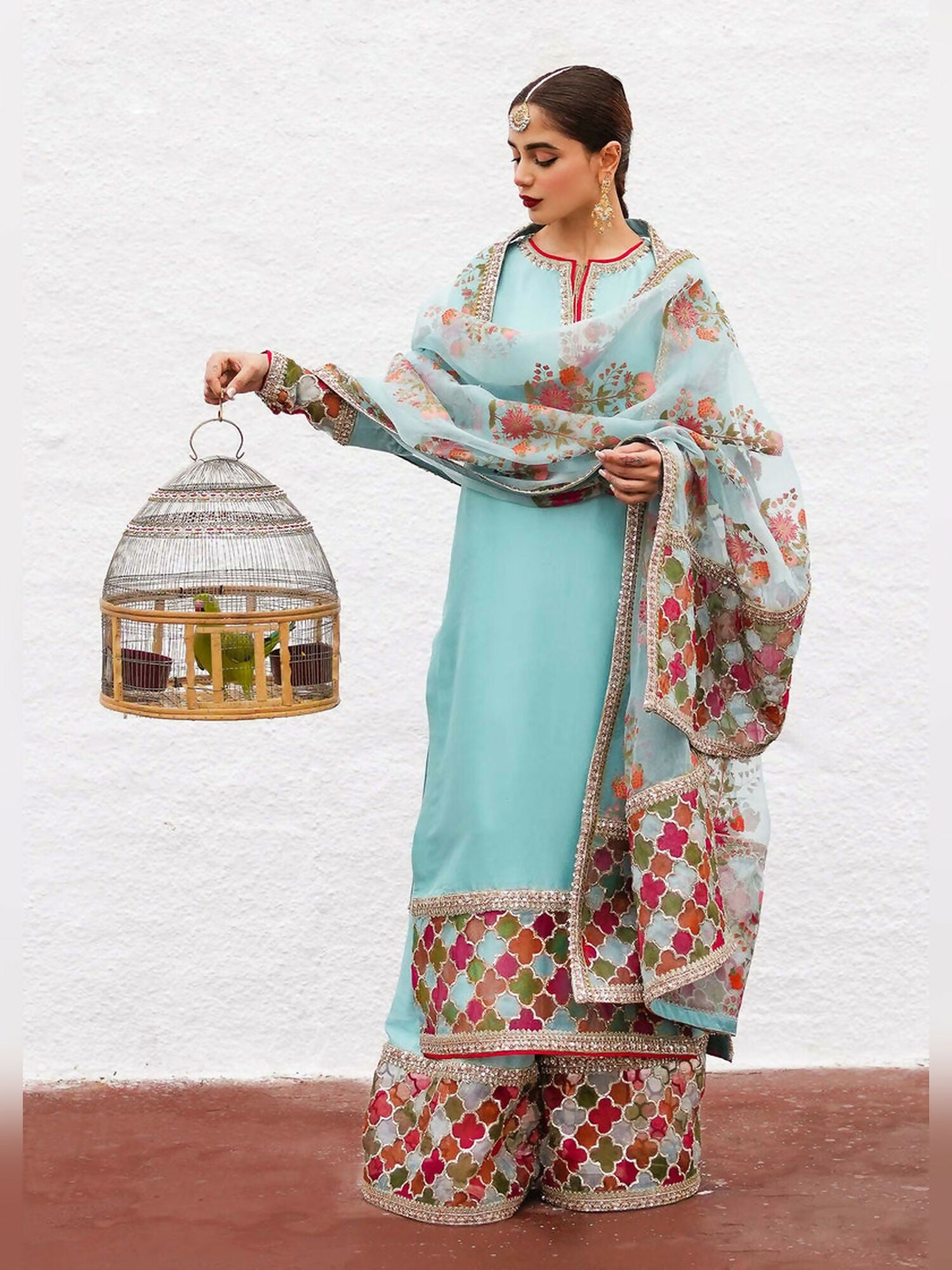 Hussain Rehar stitched 3-piece suit featuring an ice blue raw silk embellished shirt, raw silk palazzo pants with detailed border, and organza dupatta with block-printed motifs and multi-colored border.
