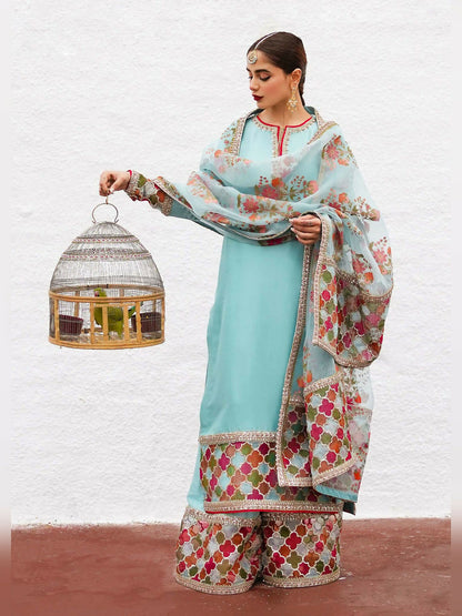 Hussain Rehar stitched 3-piece suit featuring an ice blue raw silk embellished shirt, raw silk palazzo pants with detailed border, and organza dupatta with block-printed motifs and multi-colored border.