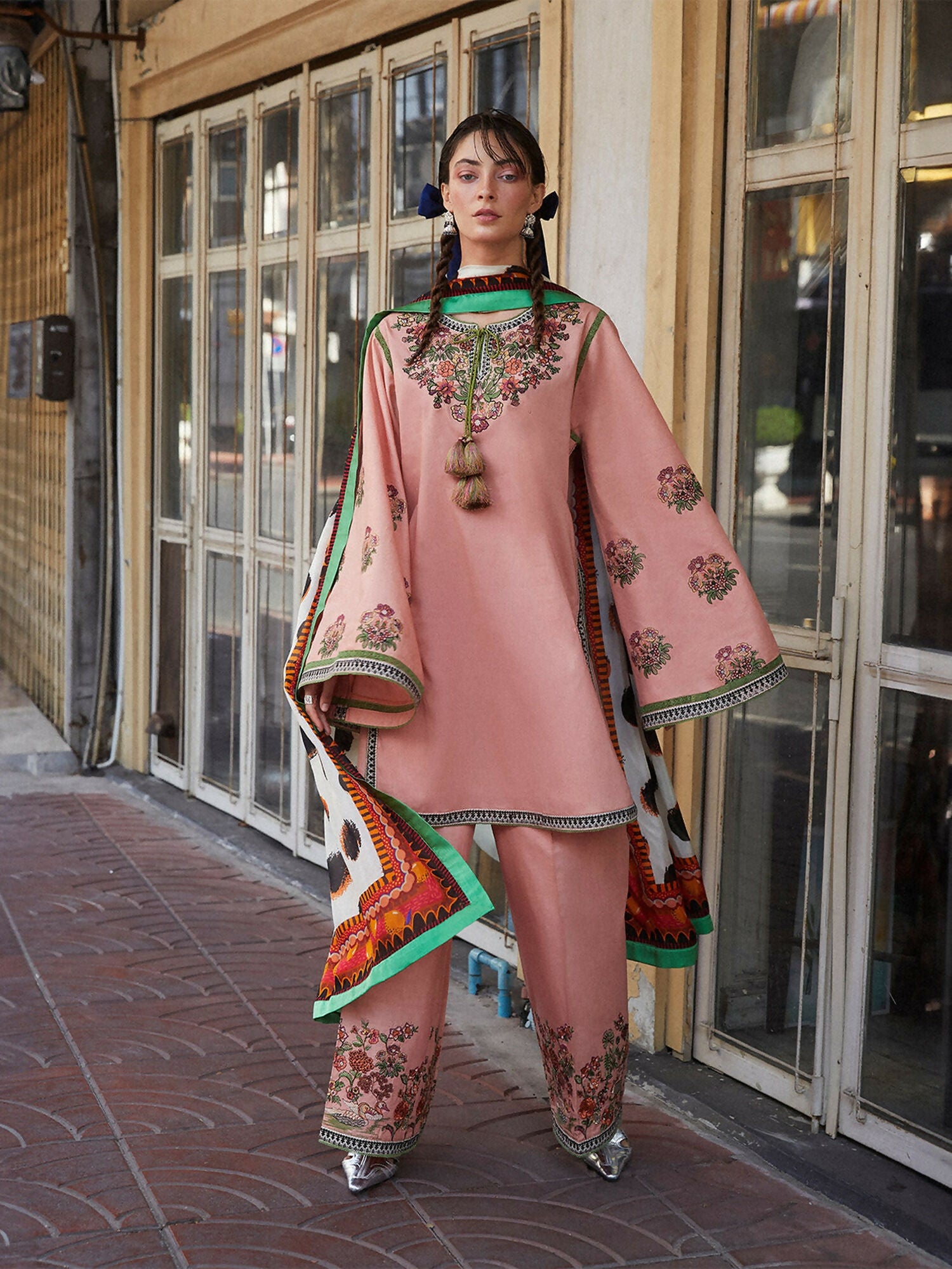 Woman wearing peach pink embroidered cotton straight shirt with flared sleeves, matching embroidered cotton plazzo pants, and printed silk dupatta, 3-piece unstitched suit.