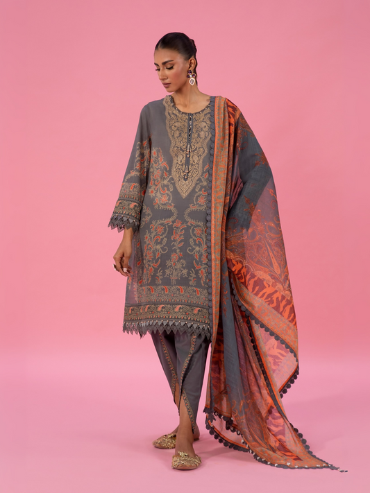 Woman wearing an unstitched 3-piece grey printed lawn suit featuring golden and subtle red motifs, paired with a matching printed dupatta and plain cambric trouser.