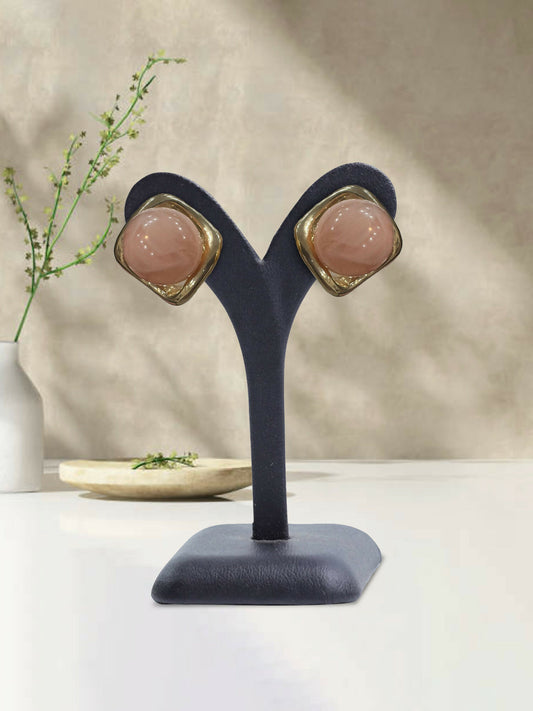 Glitter Jewellery glossy pink stud earrings with rounded dome center and metallic trim displayed on an earring stand.