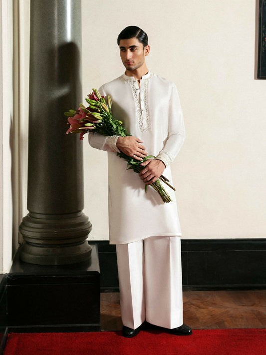 Hussain Rehar ivory raw silk kurta with hand-embellished organza neckline and cuffs, paired with wide-legged raw silk trousers.