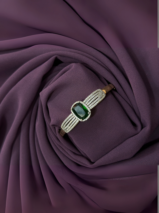 Bracelet with deep emerald-colored central crystal, surrounded by white imitation stones on a polished metallic band – 2.25-inch piece from Glitter Jewellery.