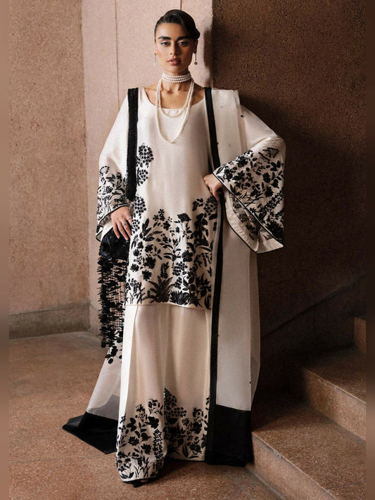 Stitched 3-piece suit by Hussain Rehar with ivory raw silk short shirt embellished in black, paired with ivory shalwar and organza dupatta with black sequin spray and satin finishing.