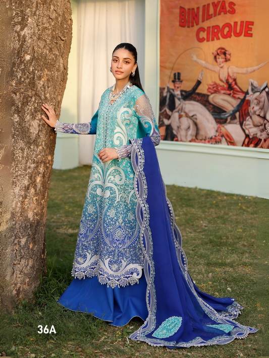 Girl standing wearing unstitched tie & dye printed suit with embroidered front, sleeve motifs, daman lace, and organza detailing, paired with chiffon dupatta featuring embroidered motifs, pallos, and side lace, and dyed cotton trouser.
