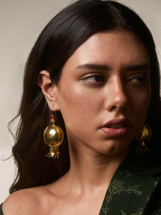 Jugnu by Hussain Rehar Pomegranate earrings with intricate gold craftsmanship, ruby-toned accents, green enamel detailing, and dangling elements, vibrant festive statement accessory.