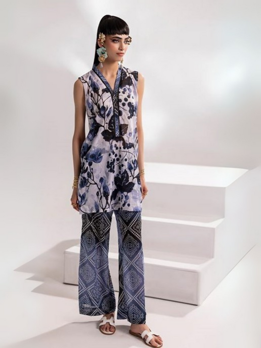 Woman wearing an off-white and navy floral printed shirt with matching geometric printed wide-leg trousers from Parizad's unstitched lawn collection.