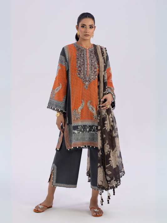 Woman wearing an unstitched 3-piece orange and black printed lawn suit with matching dupatta and dyed cambric trouser