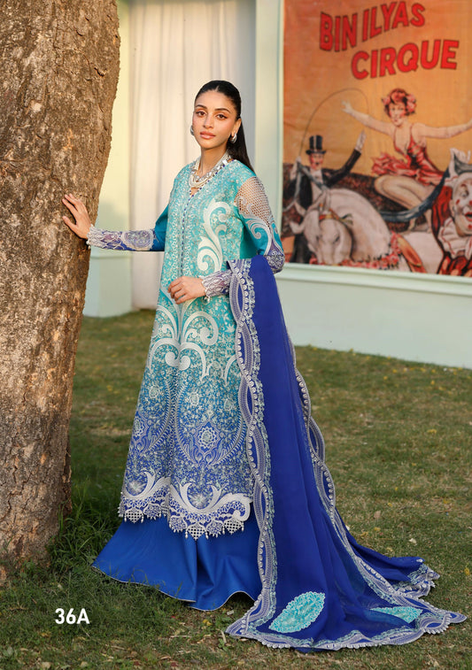 Girl standing wearing unstitched tie & dye printed suit with embroidered front, sleeve motifs, daman lace, and organza detailing, paired with chiffon dupatta featuring embroidered motifs, pallos, and side lace, and dyed cotton trouser.
