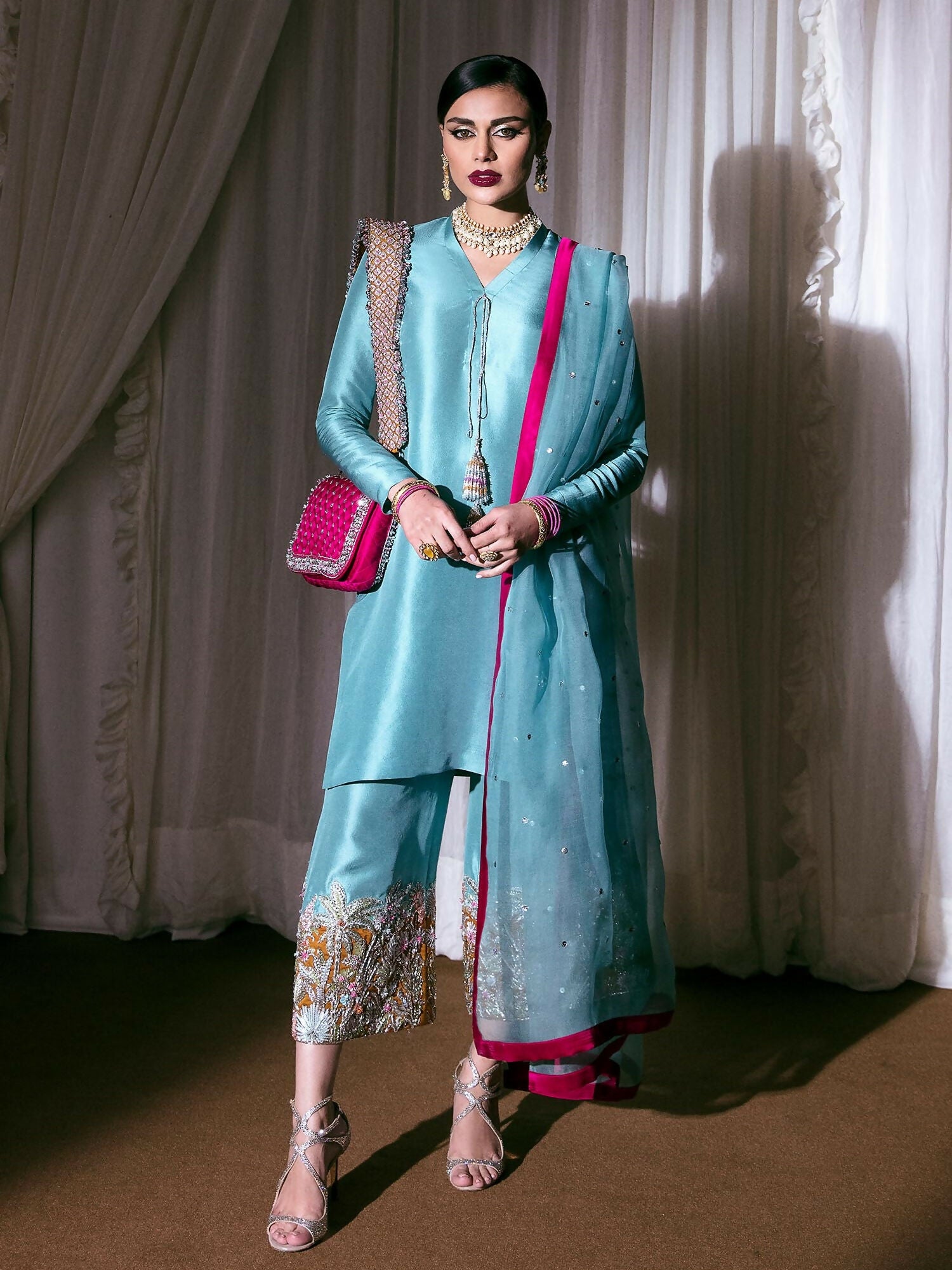 Ice blue raw silk stitched 3-piece suit Azure BNB by HussainRehar featuring a v-neckline shirt with hanging tassel, heavily embellished raw silk culottes with silver nakshi, sequins, dabka, gotta, dibbi, ghorari, multicolor bugle beads and orange piping, paired with a matching organza dupatta adorned with silver sequins and satin silk borders, perfect for festive occasions.