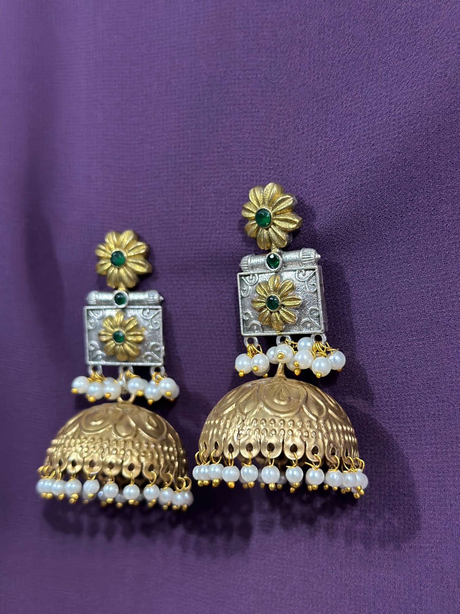 Glitter Jewellery dual-tone floral jhumka earrings with pearl clusters and green stone detailing.