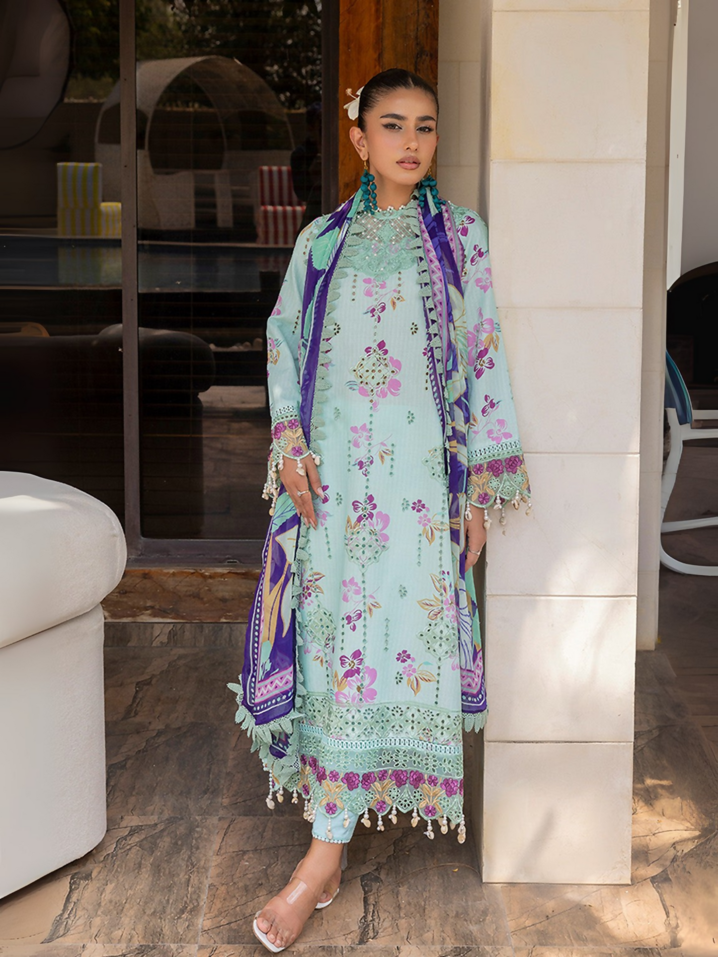 Woman wearing a sky blue unstitched 3 piece suit with colorful chikankari floral embroidery, chiffon dupatta, and cotton trouser.