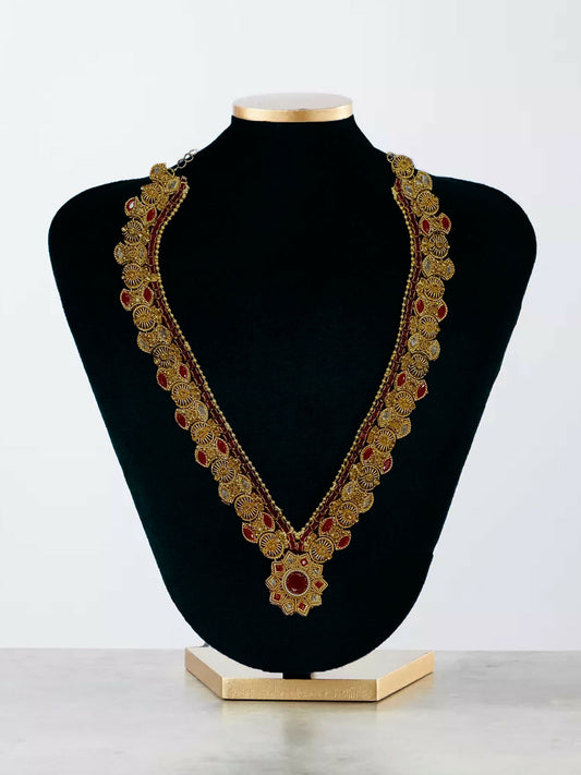Glitter Jewellery antique gold-toned long necklace with red crystals and floral design on a black display stand.