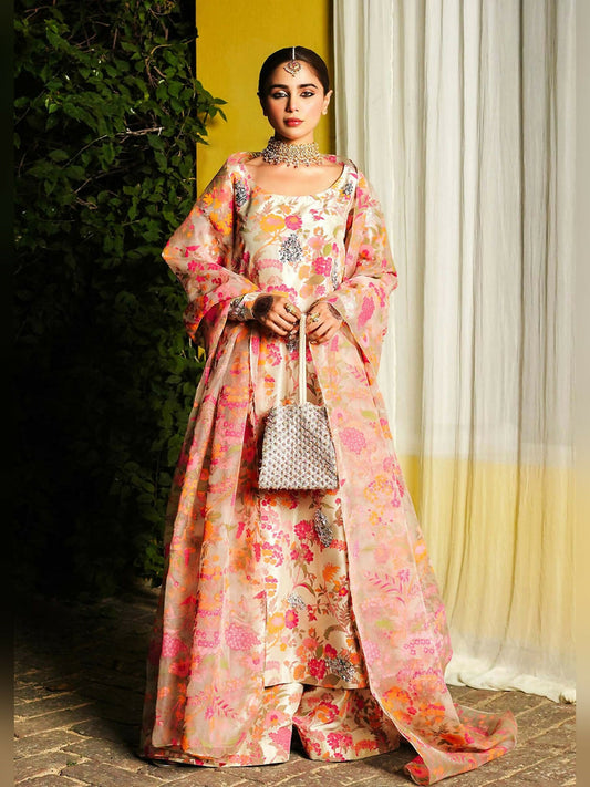 Stitched 3-piece suit by Hussain Rehar with beige long raw silk shirt featuring embellished neckline and sleeves with pita work, paired with raw silk palazzo pants and organza dupatta with kiran and golden pipe hangings.