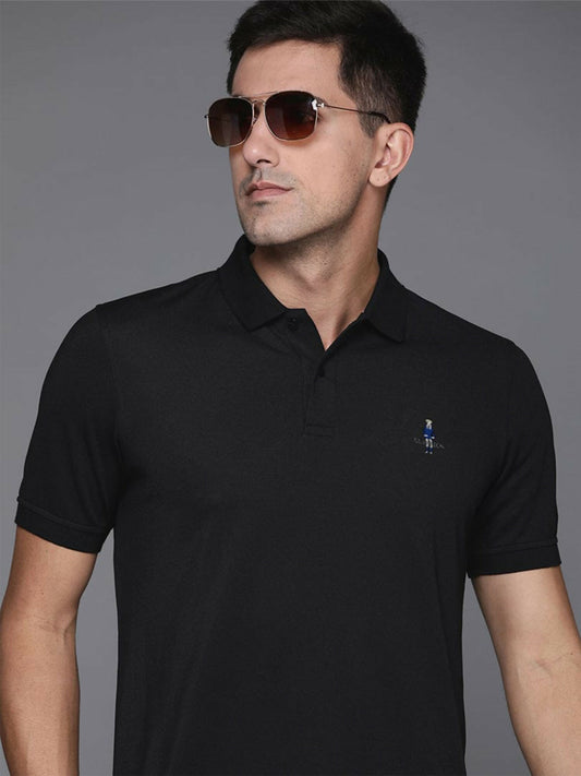 A man wearing a black cotton polo shirt with a classic knit collar, front button placket, and a fine embroidered logo on the left chest.