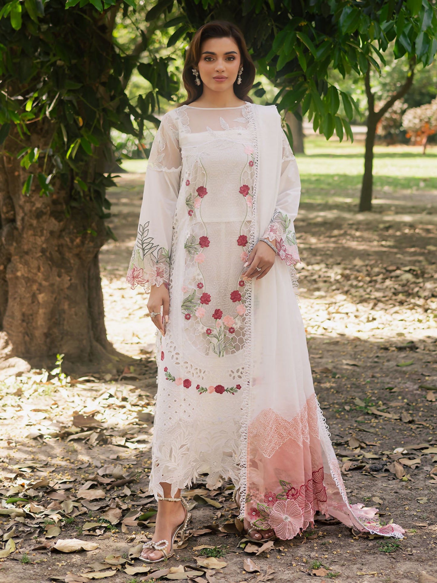 Girl standing wearing an unstitched 3-piece suit with embroidered lawn shirt front featuring center organza panel, neckline, daman, and sleeve patches, paired with an embroidered Monark dupatta and dyed Cambridge trouser with slip, ideal for festive or formal wear.