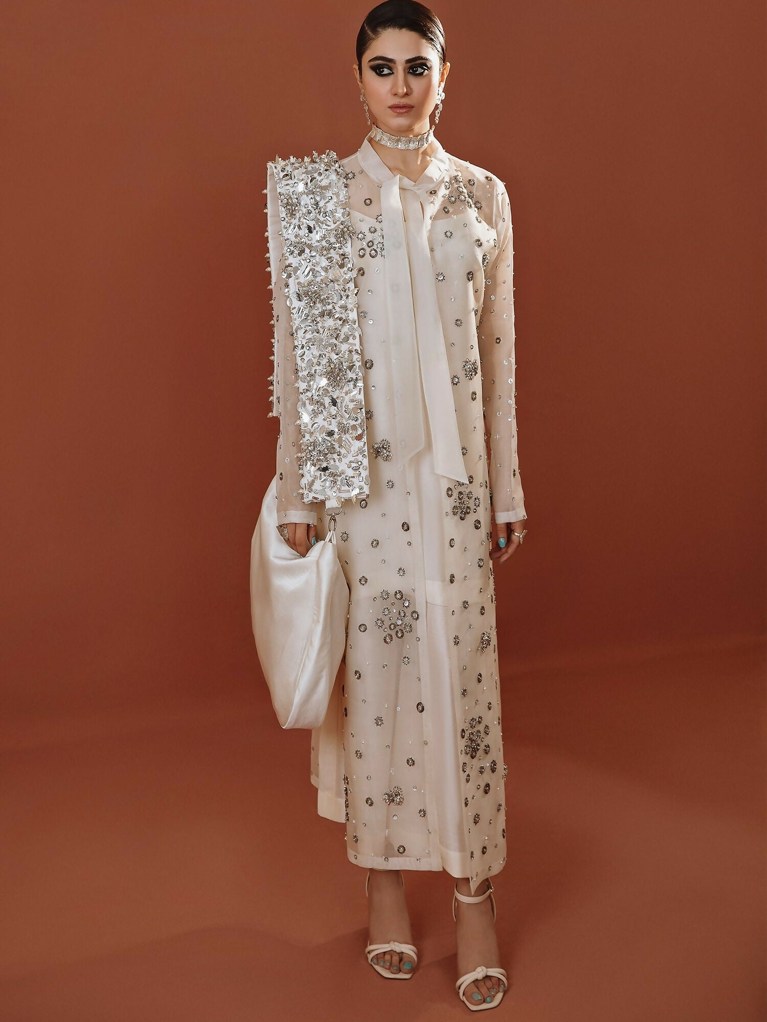 White long organza jacket outfit with silver embellishments, straight pants, and organza dupatta by Hussain Rehar.