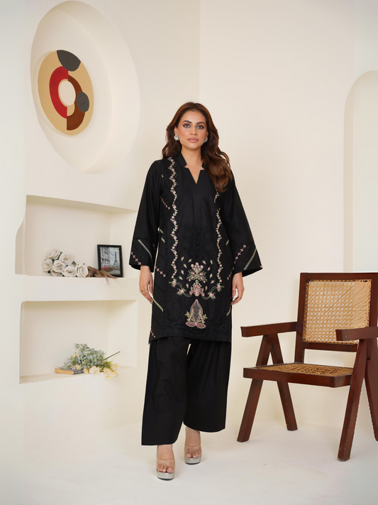 Woman wearing a black 2-piece suit with pastel floral embroidery and eyelet detailing, paired with a plain trouser