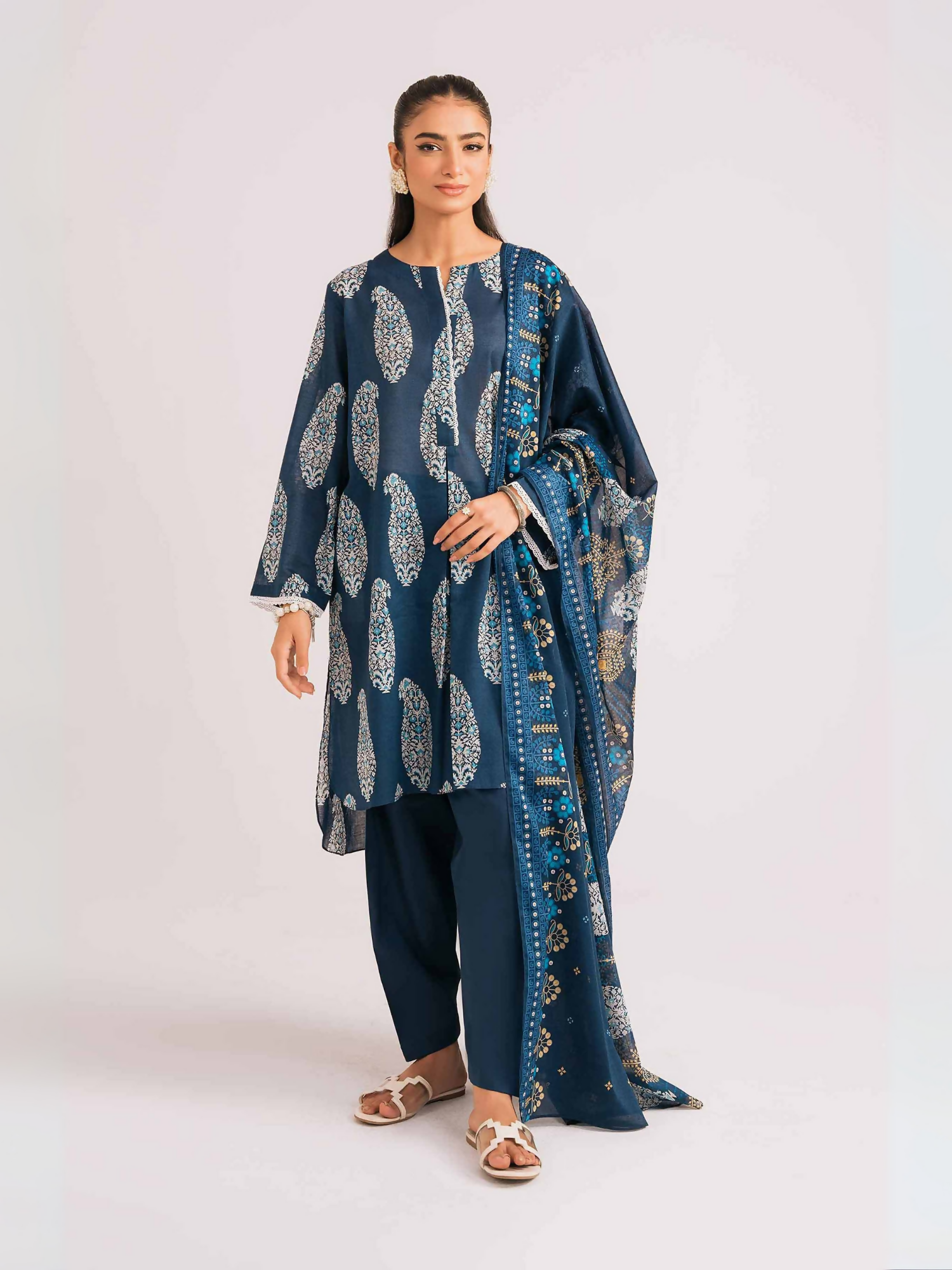 Nishat unstitched 3-piece lawn suit with paisley print, voile dupatta, and cambric trouser in dark blue.