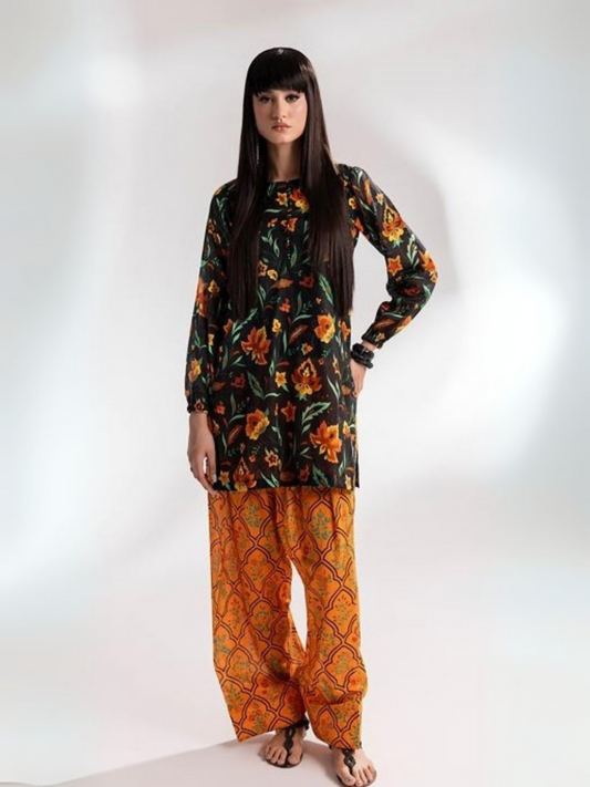 Woman wearing a black floral printed shirt with orange traditional printed trousers from Parizad’s unstitched lawn collection.