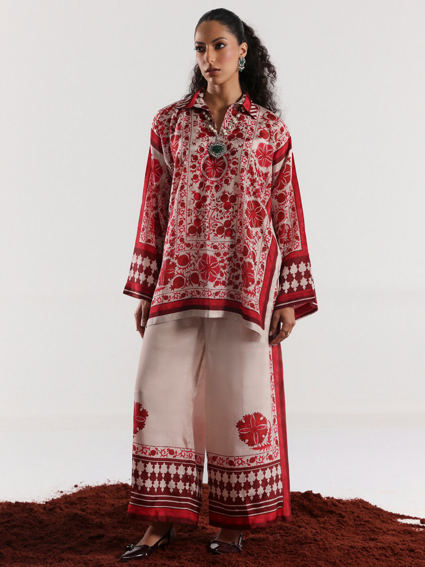 Model wearing a red and off-white digital printed silk co-ord set featuring bold floral motifs and geometric border detailing on a relaxed silhouette.