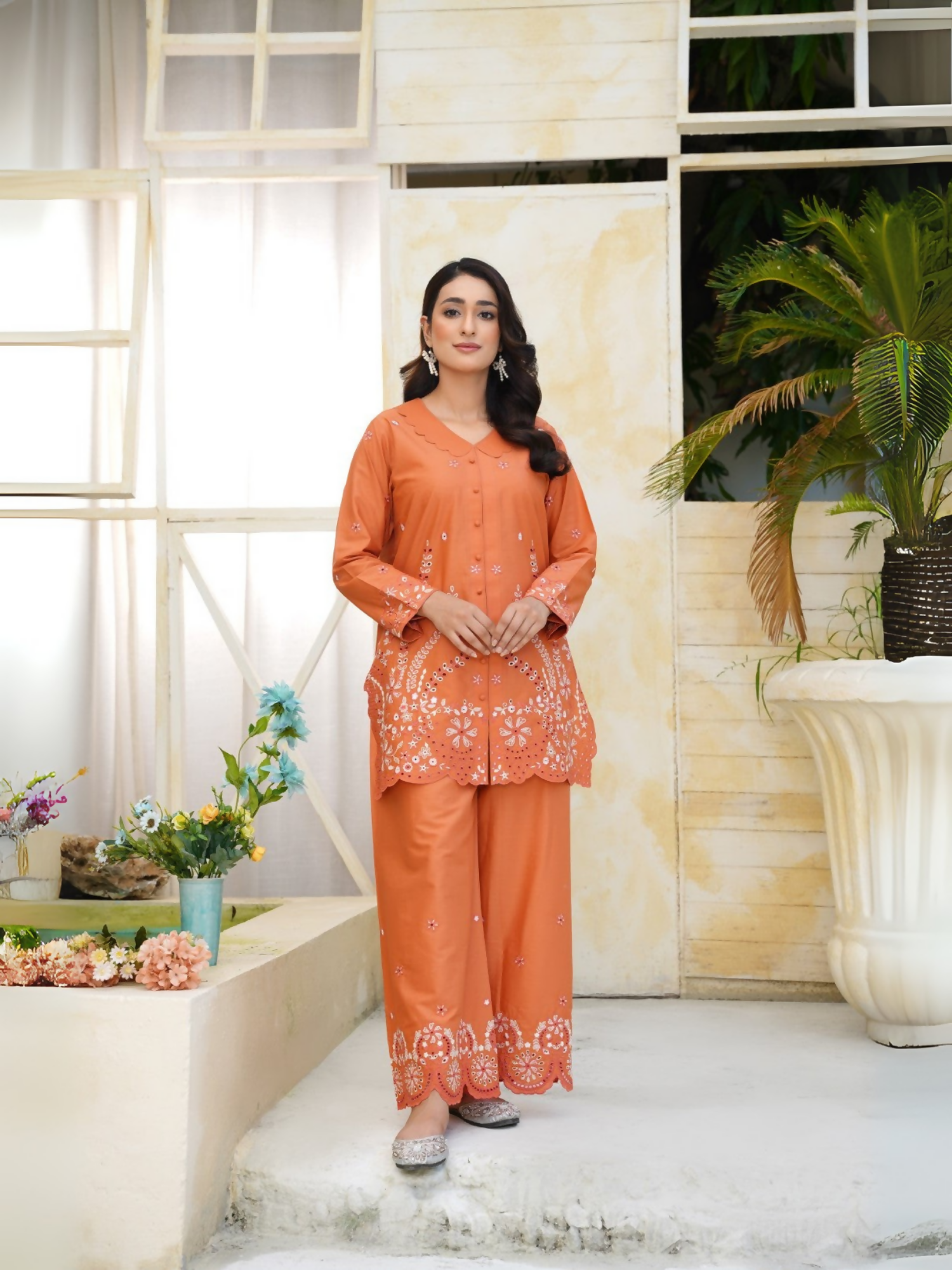 Girl wearing Trends Forever burnt orange lawn cotton embroidered kurta with white floral motifs, mirror work, and matching shalwar; stitched 2-piece suit