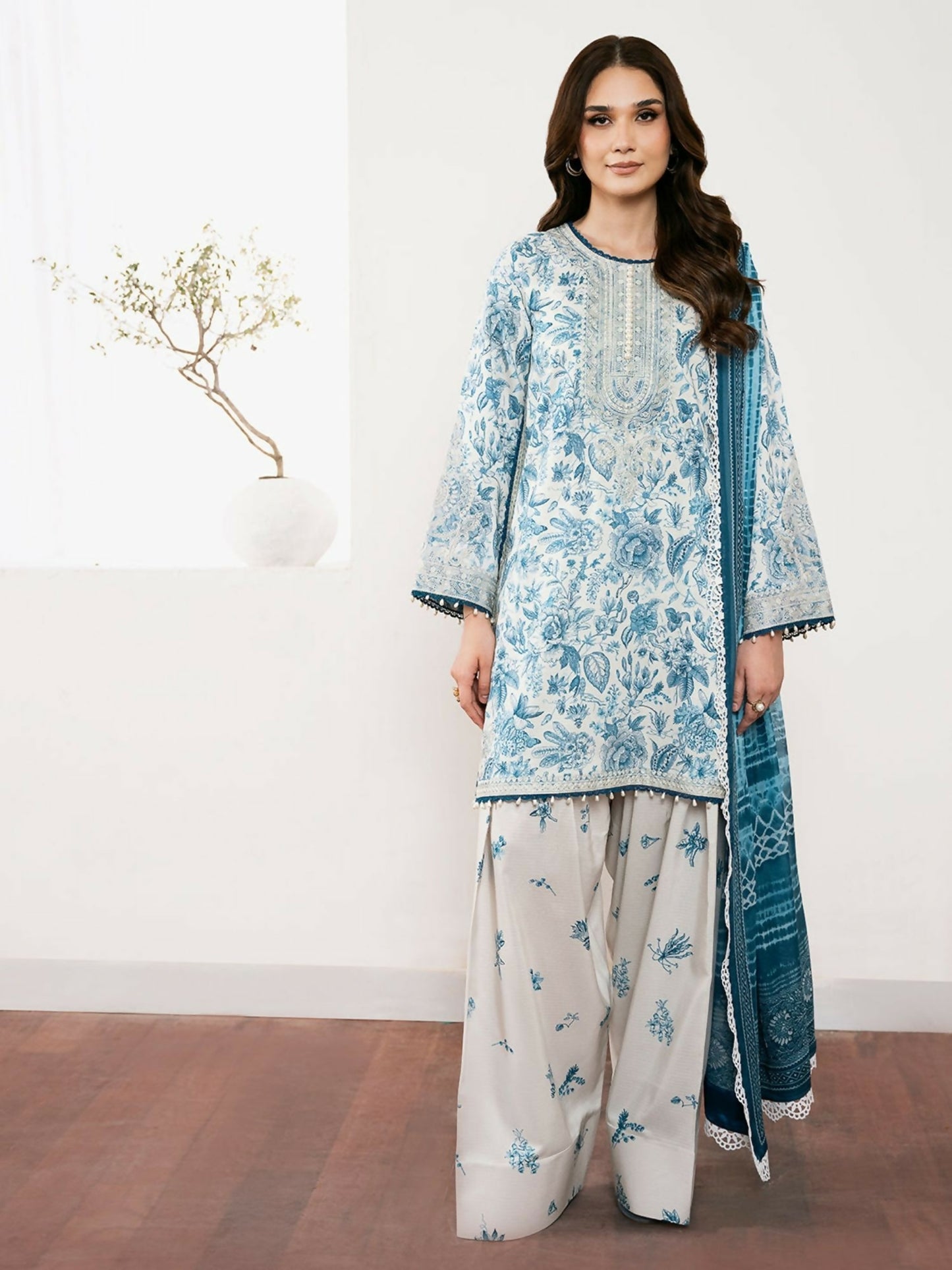 Unstitched 3-piece suit from Binilyas Noura Summer Edit featuring digitally printed lawn shirt with embroidered neck, daman motifs, and organza laces, paired with digital printed dupatta and cotton trouser.