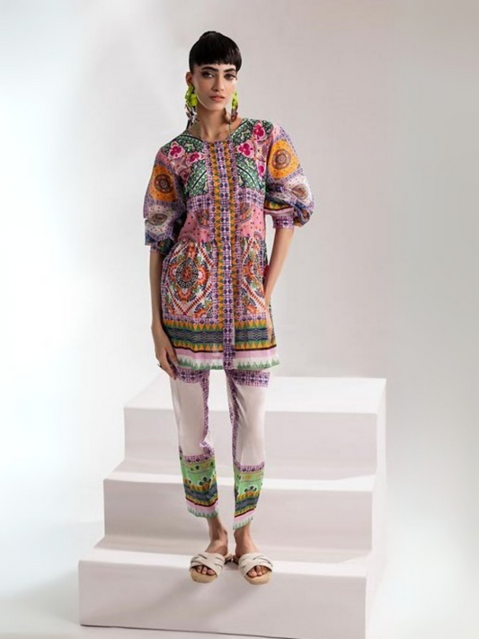 Woman wearing a vibrant mosaic-printed shirt in bold shades of orange, pink, green, and purple, paired with a matching printed trouser from Parizad's unstitched lawn collection.