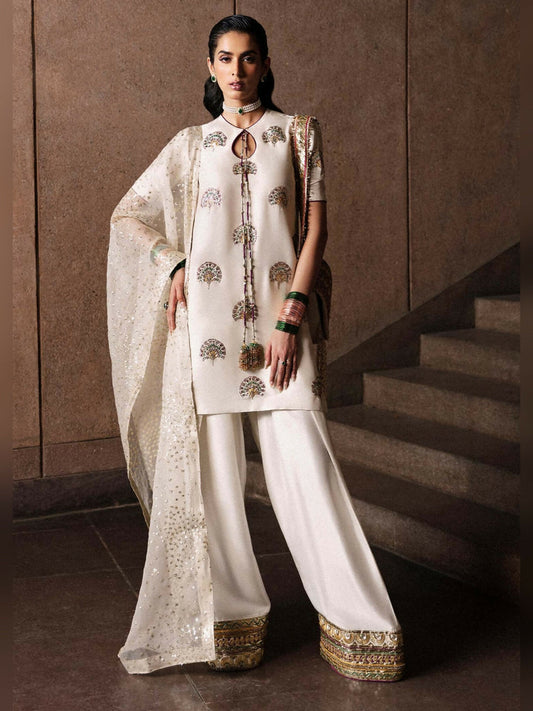 Stitched 3-piece suit by Hussain Rehar with ivory raw silk short shirt embellished with mukesh, naqshi, and colorful threadwork motifs, paired with shalwar with gota border and organza dupatta with sequin spray and lappa finishing.