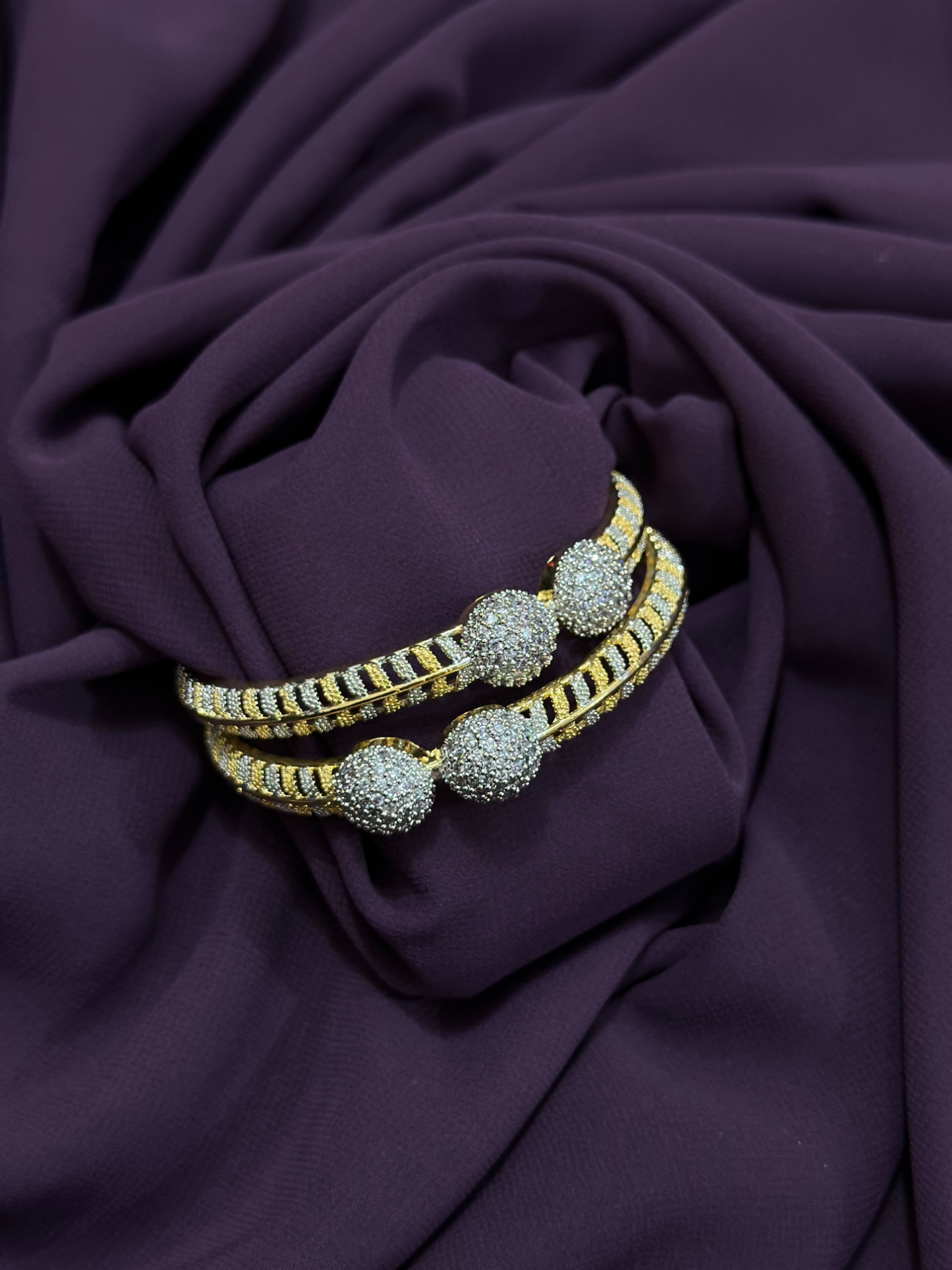 Close-up of two individual two-toned karas featuring pavé-textured spheres, crystal detailing, and black enamel accents – statement pieces from Glitter Jewellery.